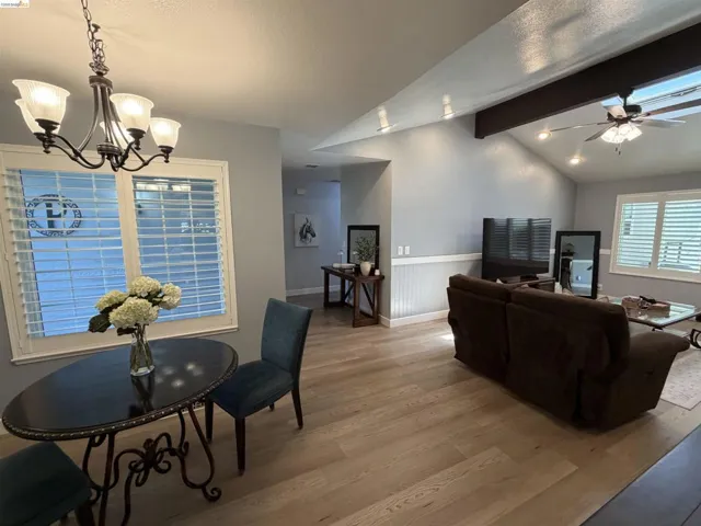 Open-concept living space featuring vaulted ceilings, wood-finish flooring, and plantation shutters