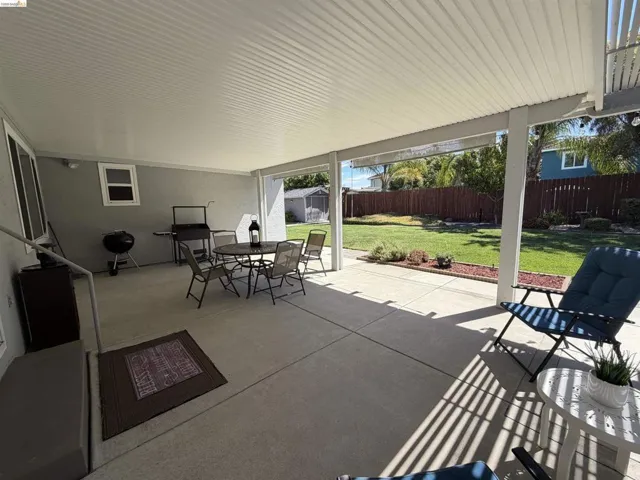 Expansive concrete patio with a full patio cover, providing shade and outdoor living space