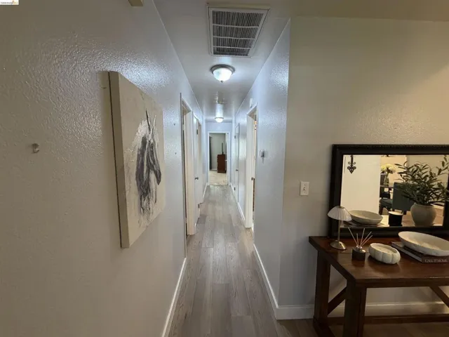 Hallway featuring recessed ceiling lighting, wood-finish flooring, white baseboards, and a light gray wall finish