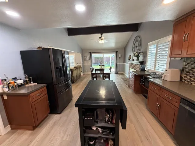 Open-concept living space featuring vaulted ceilings with exposed beam, recessed lighting, and wood-finish flooring