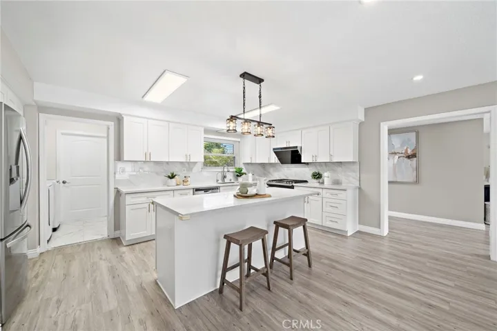 Kitchen has Quartz Counters and Center Island with Seating, Custom Self-Closing Cabinetry with Pull-Outs, and Stainless Appliance