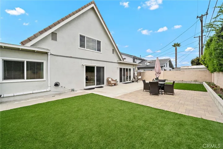 Backyard is designed for easy-care outdoor living with artificial turf and concrete patio areas, creating an ideal setting for entertaining, relaxing, and enjoying refreshing ocean breezes.