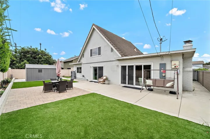 Tranquil and spacious backyard is designed for easy-care outdoor living with artificial turf and concrete patio areas, creating an ideal setting for entertaining, relaxing, and enjoying refreshing ocean breezes.