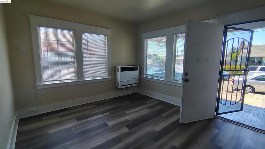Entry area featuring wood-finish flooring, white trim, and a wall-mounted unit