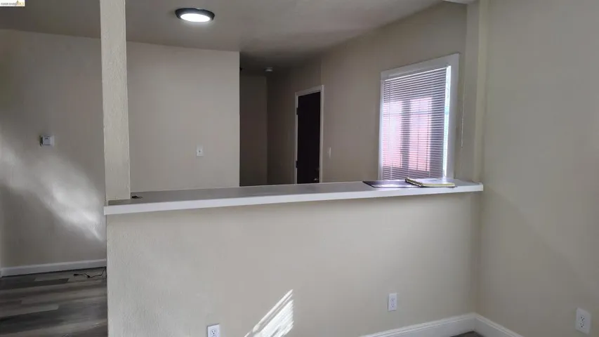 Interior space featuring a built-in counter surface with an overhead window, neutral wall tones, wood-finish flooring, and a flush-mount ceiling light fixture