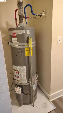 Water heater with a Rheem Performance series unit, featuring a water heater pan and wall-mounted water shut-off valve
