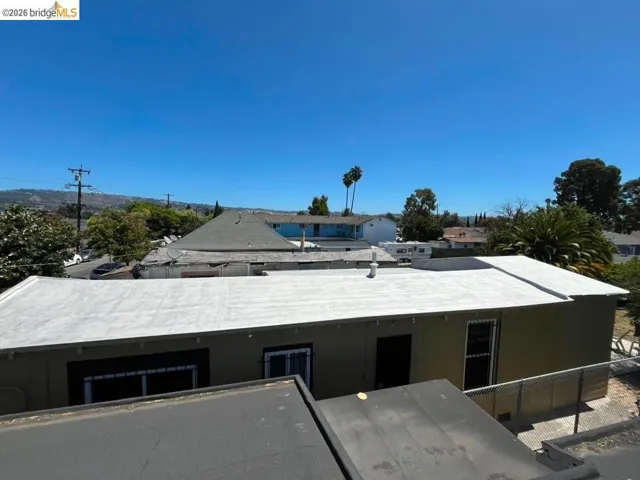 Flat roof property with stucco exterior, rear fencing, and perimeter landscaping