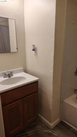 Bathroom featuring a vanity with a white countertop and an integrated sink, a two-door wood-finish cabinet, and a chrome faucet
