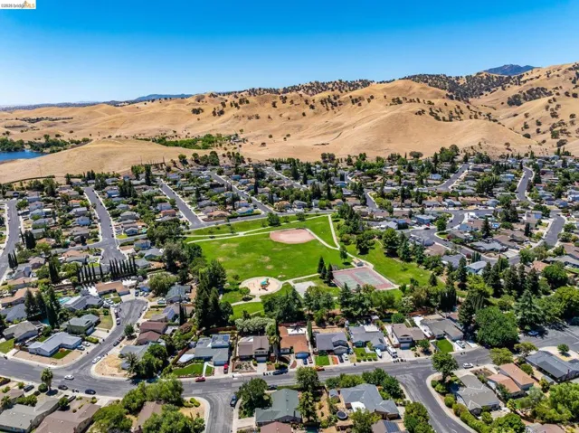 Aerial perspective showcasing a residential community with a central park, a baseball field, and tennis courts