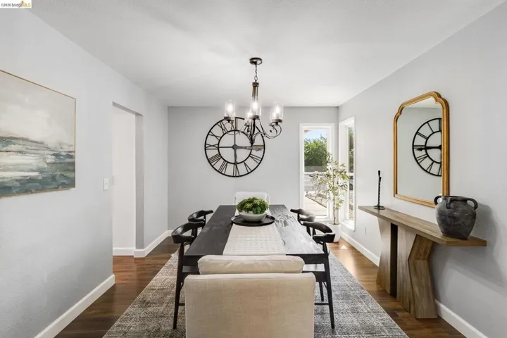 Dining area featuring wood-finish flooring, a contemporary chandelier, light-toned walls, and multiple windows