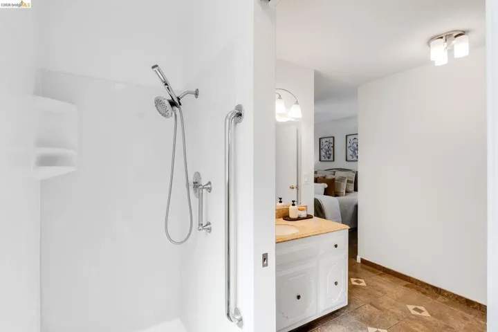Shower enclosure featuring a handheld showerhead and grab bar