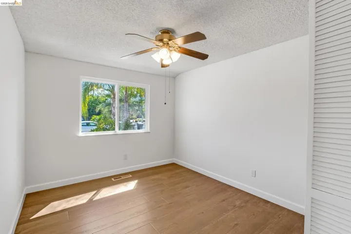 Light-filled room featuring wood-finish flooring, white baseboards, and a contemporary ceiling fan