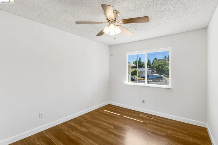 Room featuring wood-finish flooring, white baseboards, and a ceiling fan with integrated lighting