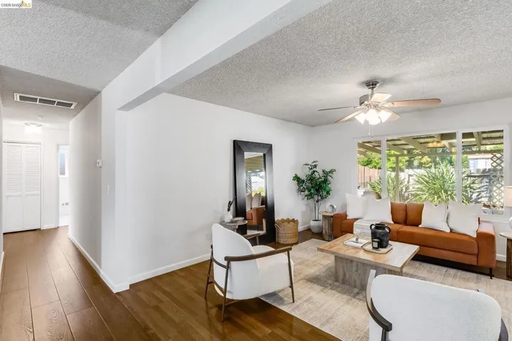 Open-concept living area featuring wood-finish flooring, a contemporary ceiling fan, and large picture windows