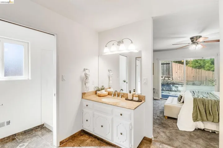 Bathroom featuring a single vanity with a granite-style countertop, undermount sink, and a three-light fixture