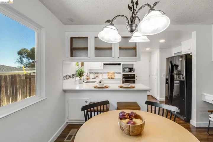 Kitchen and dining area featuring a breakfast bar, white cabinetry with glass inserts, recessed lighting, and a black appliance package