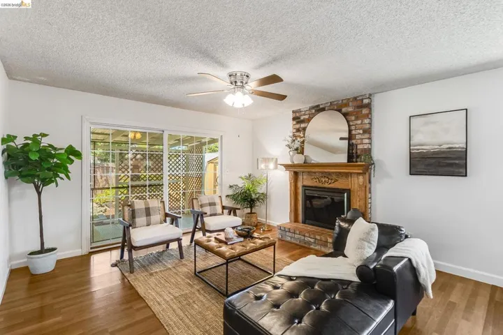 Living room featuring wood-finish flooring, a brick fireplace with a wood mantel, and sliding glass doors to the exterior