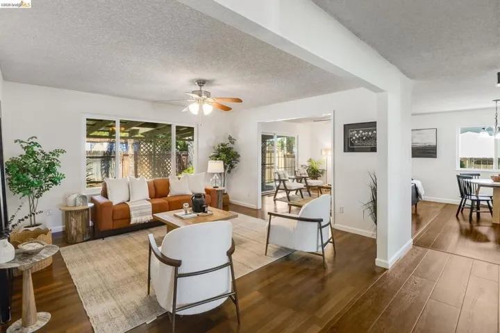 Open-concept living area featuring wood-finish flooring, white walls, and a ceiling fan