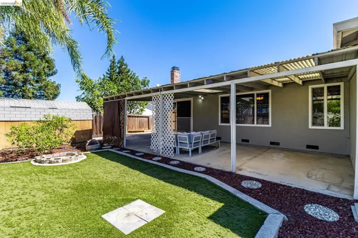 Expansive backyard featuring artificial turf, a built-in stone fire pit, and a stucco exterior