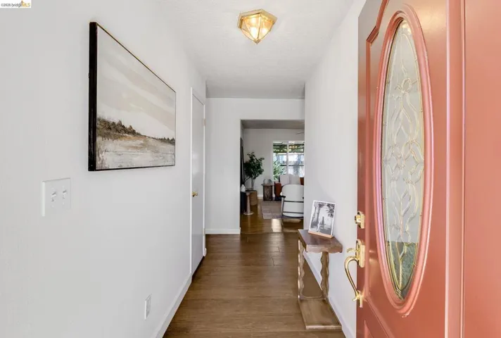 Entryway featuring a decorative front door with an oval-shaped glass insert, brass hardware, wood-finish flooring, and a flush-mount ceiling light fixture