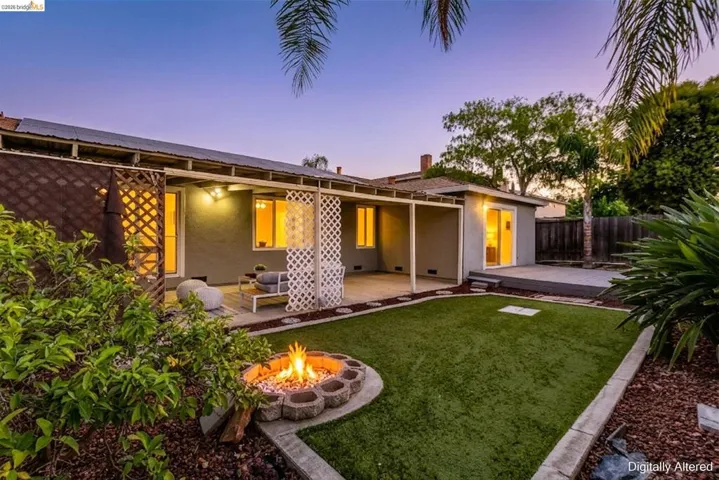 Expansive backyard featuring a central fire pit, artificial turf lawn, and mature landscaping