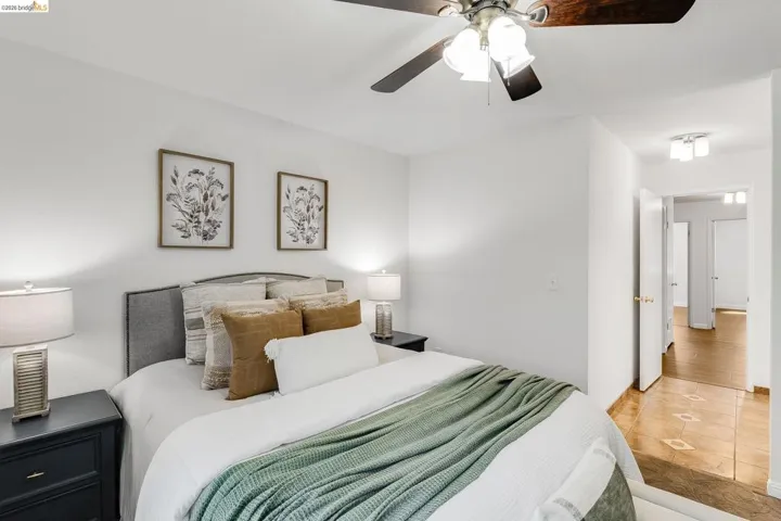Bedroom featuring a ceiling fan with integrated lighting, a paneled headboard, and two bedside tables