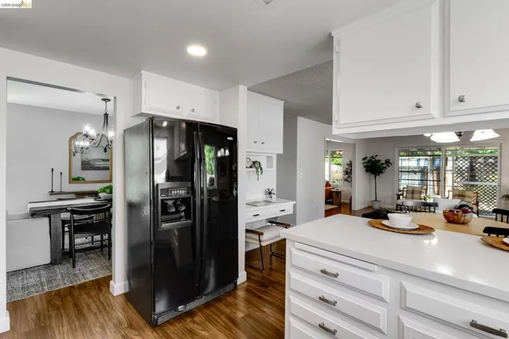 Kitchen featuring white cabinetry with brushed nickel hardware, a black side-by-side refrigerator, recessed lighting, and wood-finish flooring