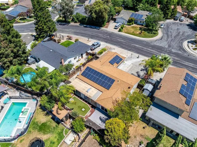 Residential property featuring a swimming pool, mature landscaping, and a solar panel array