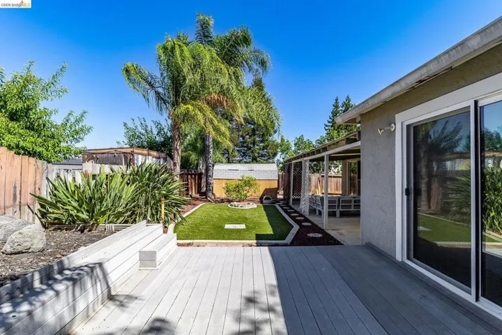 Expansive backyard featuring a multi-level deck, a covered patio area, and a central artificial turf lawn