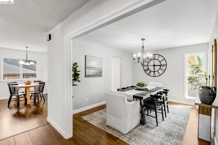 Formal dining area featuring a modern chandelier, light neutral paint, and wood-finish flooring