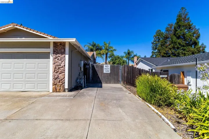 Concrete driveway leading to a two-car garage with a panel door and stone veneer accent