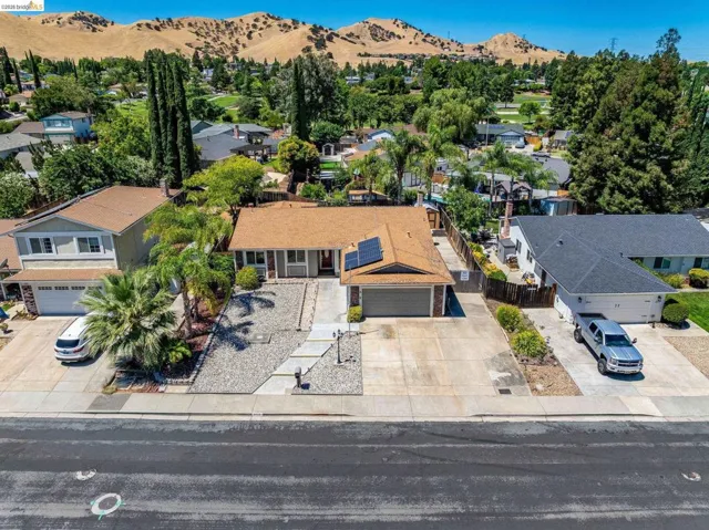 Single-story residence featuring a brown shingle roof with solar panels, an attached two-car garage, and a light-toned exterior with brick accents