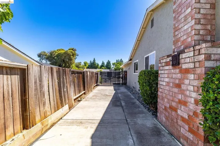 Side yard featuring a concrete pathway, privacy fencing, and exterior brickwork