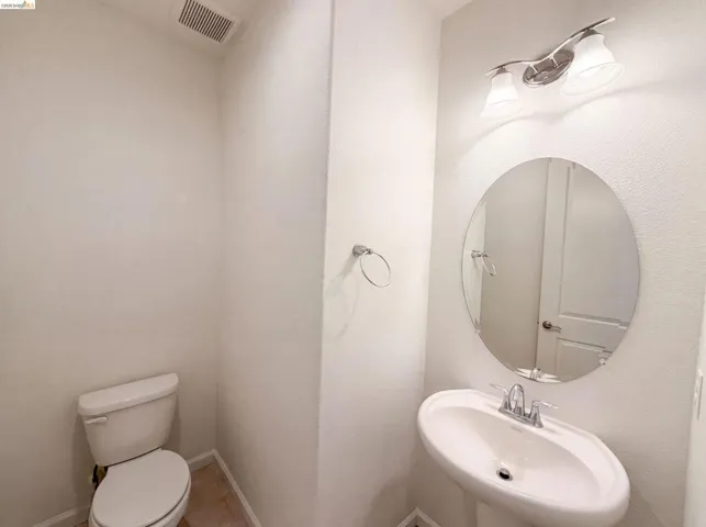 Pedestal sink with chrome faucet, complemented by an oval wall mirror and a two-light vanity fixture