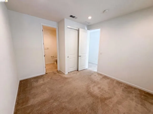 Carpeted room featuring a double bifold closet, recessed lighting, and white baseboards
