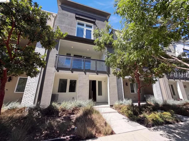 Contemporary townhome exterior featuring a clean-lined facade, a second-story balcony with metal railings, and a ground-level entrance