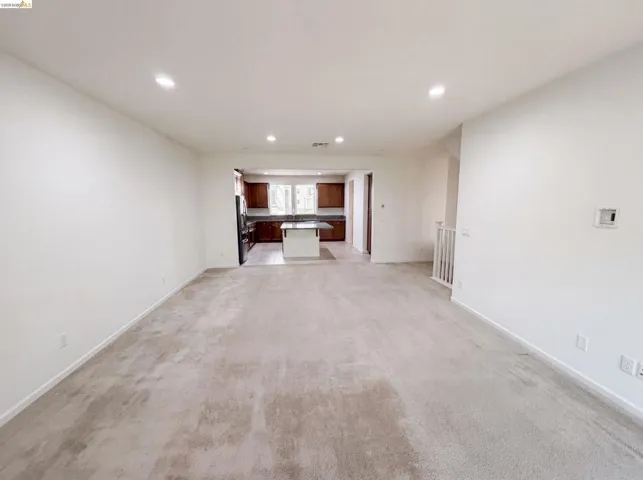 Expansive living area with light-toned carpeting and recessed lighting