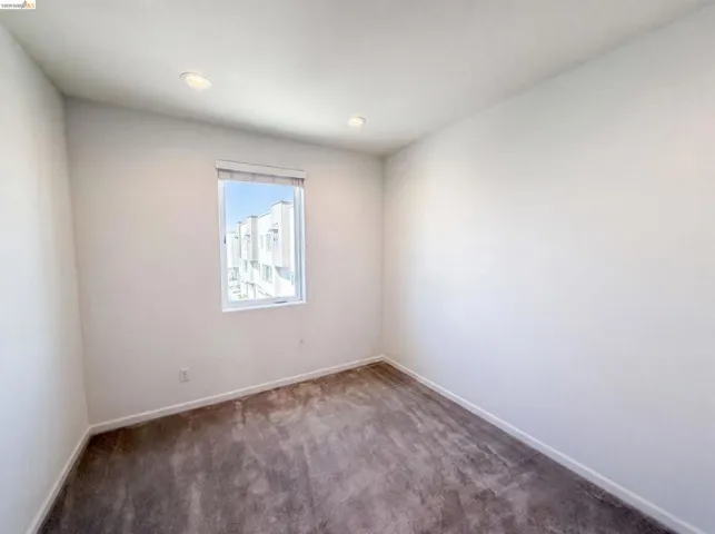 Room featuring a window with roller blinds, recessed lighting, and grey carpet flooring