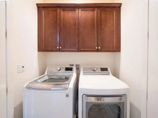Dedicated laundry area featuring overhead wood-finish cabinetry