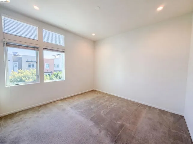 Bright room featuring large windows, recessed lighting, white walls, and neutral-toned carpeting