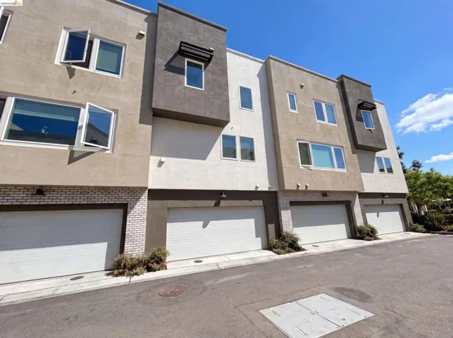 Modern multi-story exterior with varied stucco finishes, multiple windows, and individual garage access