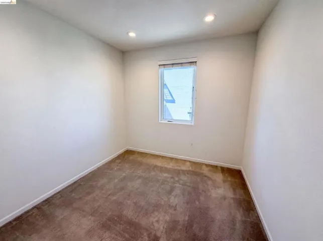 Room with neutral wall paint, brown carpet flooring, recessed lighting, and a single window with blinds