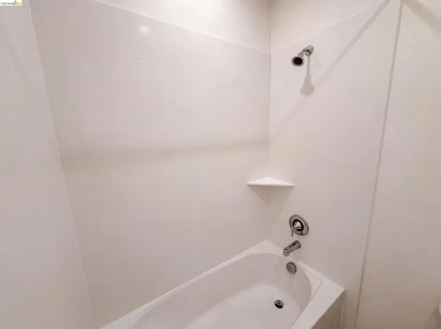 Bathtub and shower combination featuring an integrated corner shelf and chrome fixtures