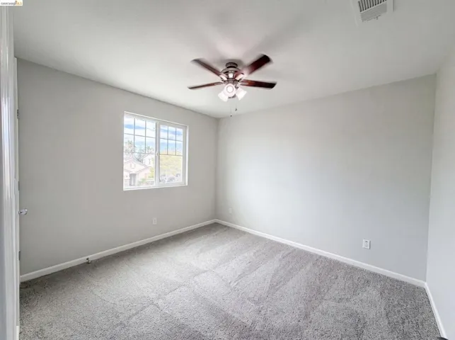 Room featuring light gray wall paint, gray carpet flooring, and a white-framed window with grid panes