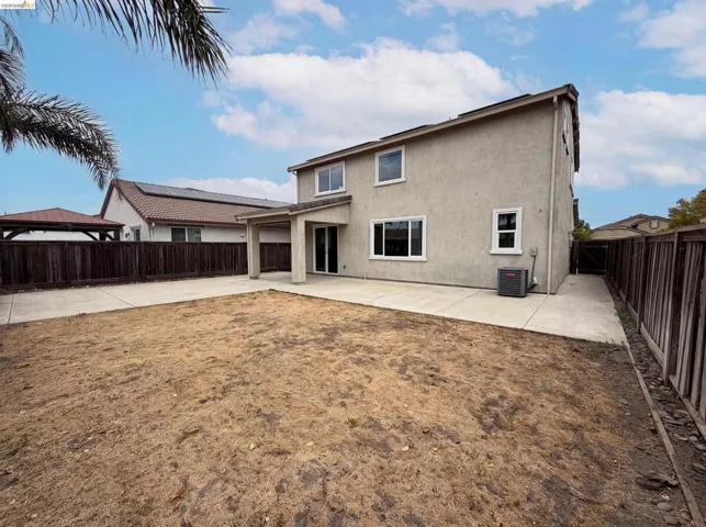 Spacious rear yard featuring a concrete patio, covered outdoor area, and a privacy fence