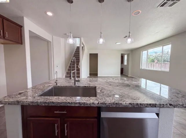 Kitchen island featuring a stainless steel sink, gooseneck faucet, and stone-finish countertop