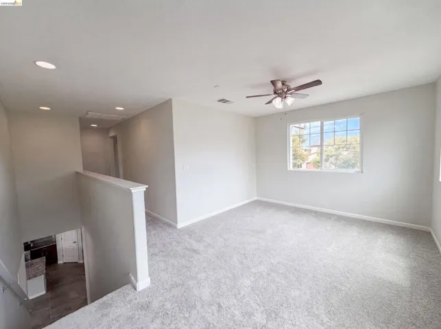 Carpeted loft space featuring a multi-pane window, ceiling fan with integrated lighting, and recessed ceiling lights