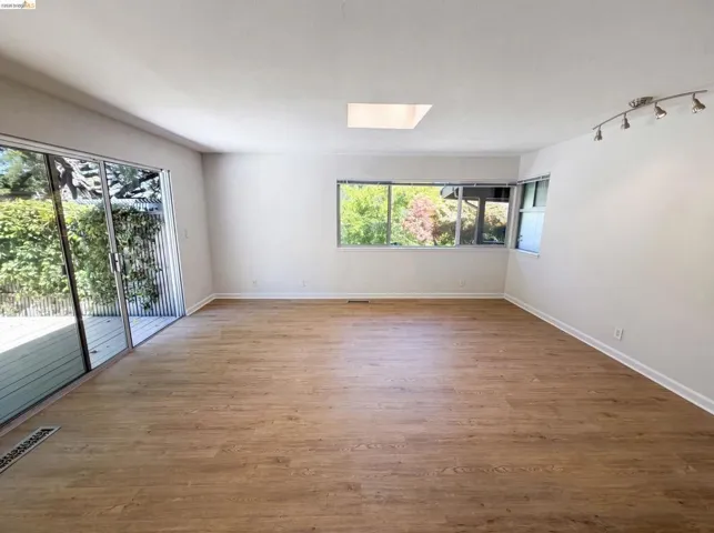 Open concept room featuring wood-finish flooring, white walls, and a skylight