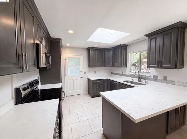 Contemporary kitchen featuring dark wood-finish cabinetry and light-toned countertops
