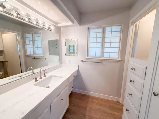 Bathroom vanity featuring a single undermount sink, a white countertop, and extensive built-in cabinetry with drawers